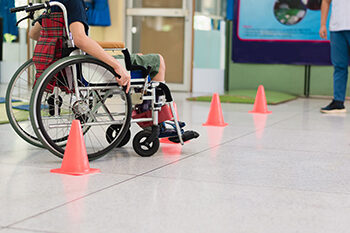 Child in a wheelchair practicing skills with an occupational therapist