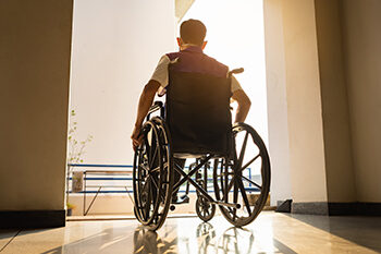 Man in wheelchair pushing himself through doorway.